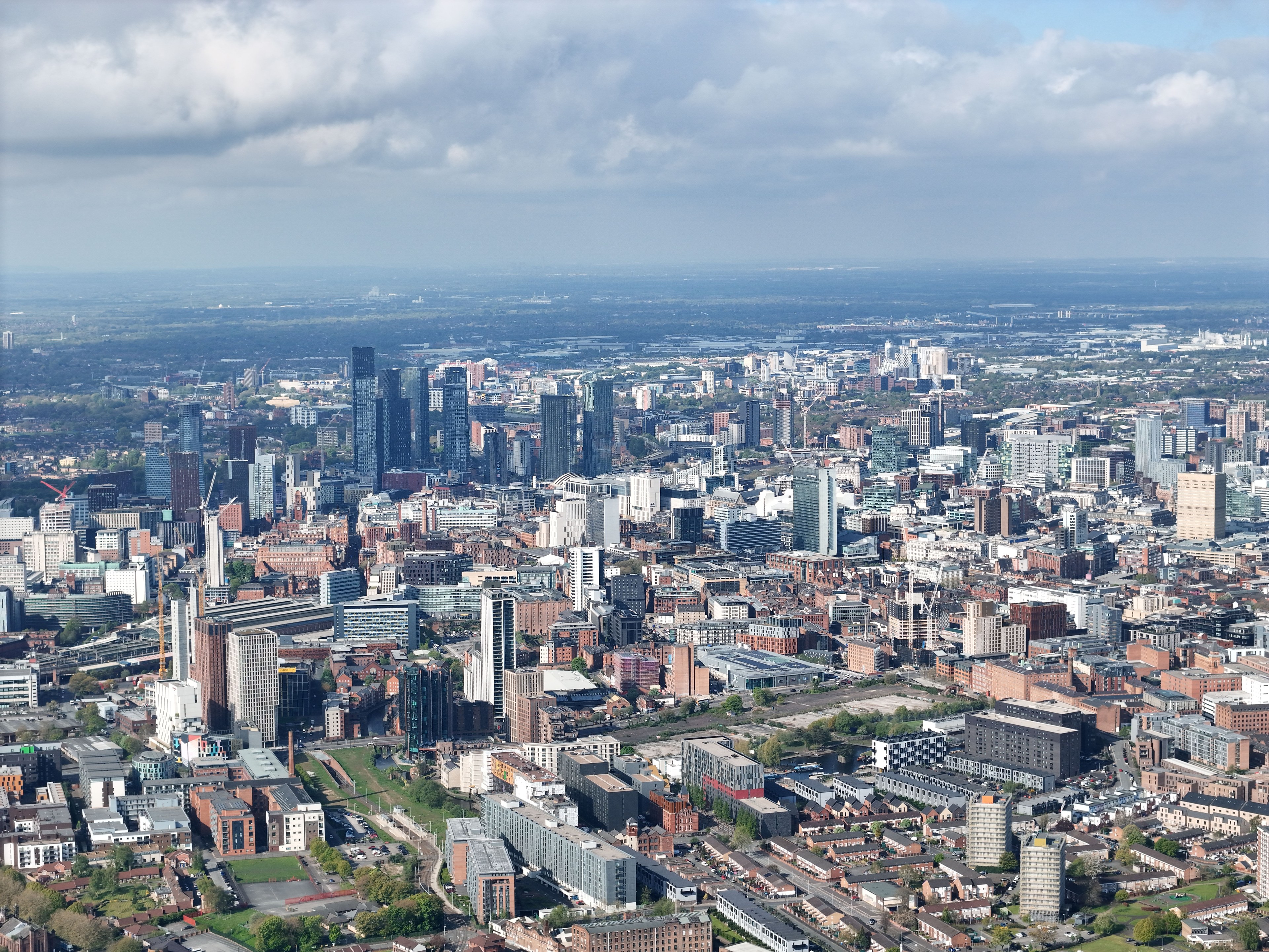 Stunning aerial photograph of Manchester's urban skyline showcasing modern architecture under scattered clouds.