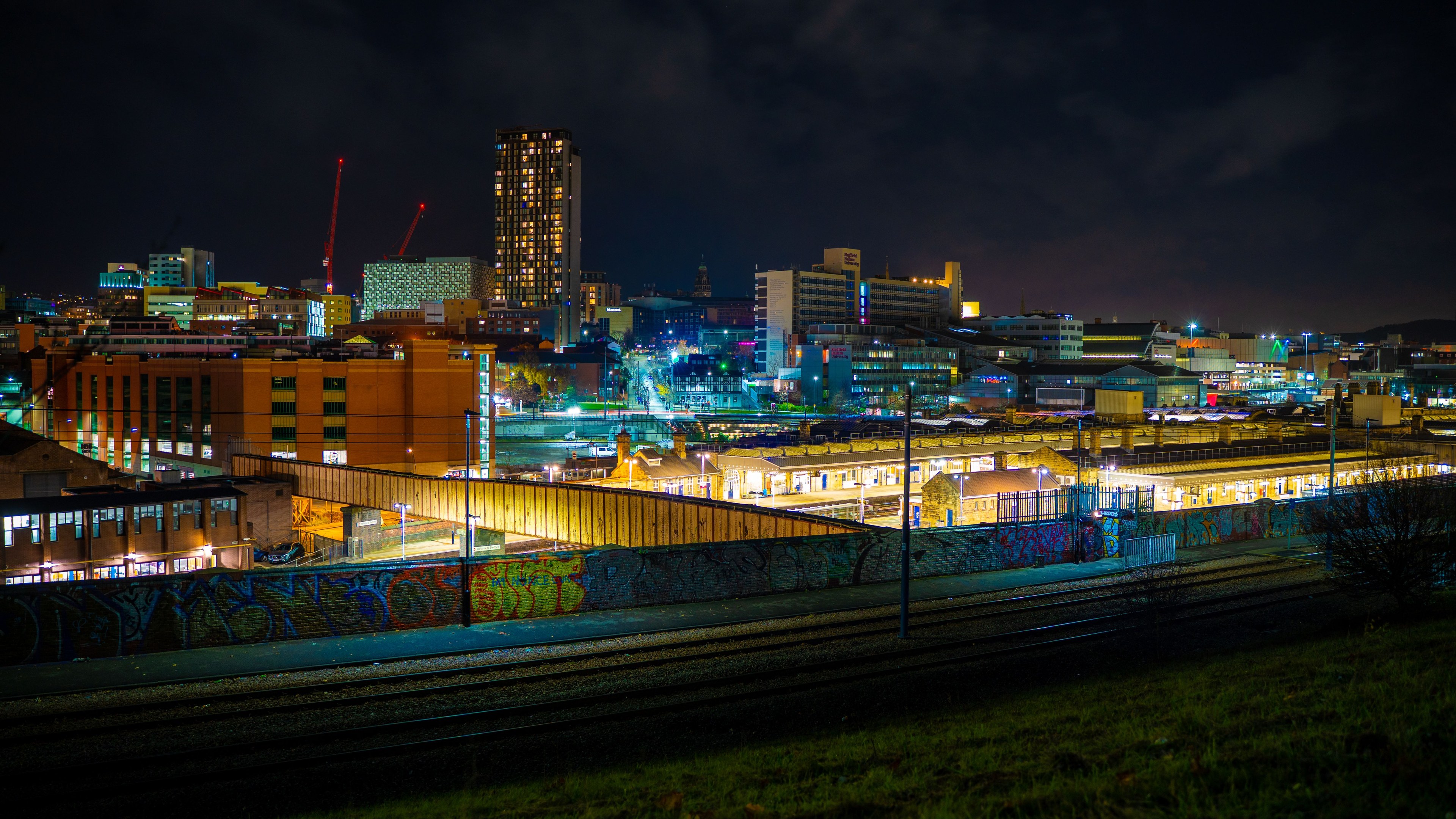 Illuminated night view of Sheffield cityscape showcasing modern architecture and urban life.